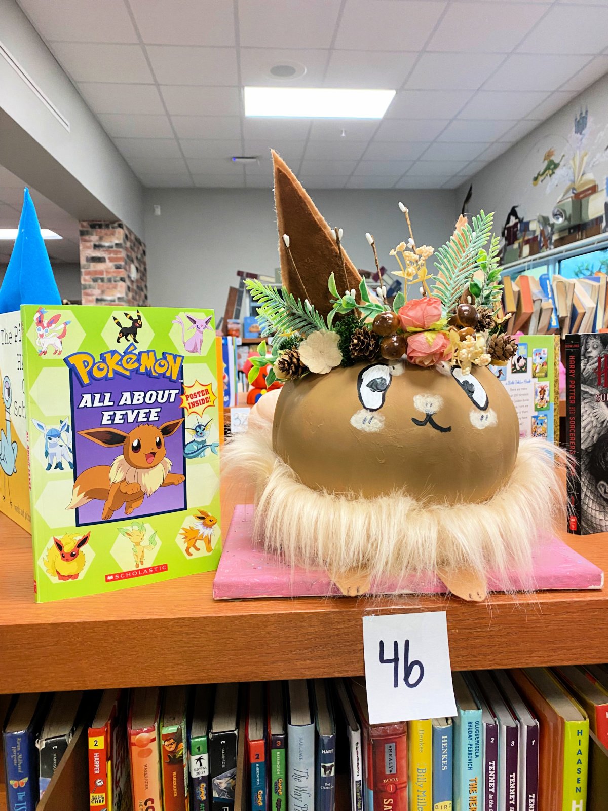 Brown Eevee pumpkin next to a Pokemon book.