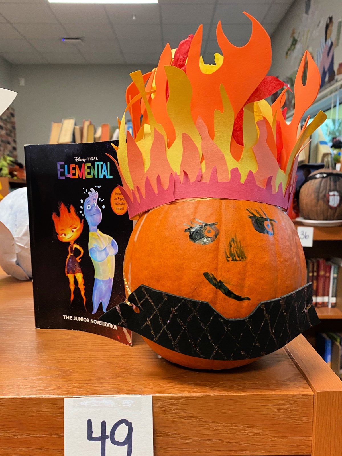 Orange pumpkin with flames on top next to a black Elemental book.