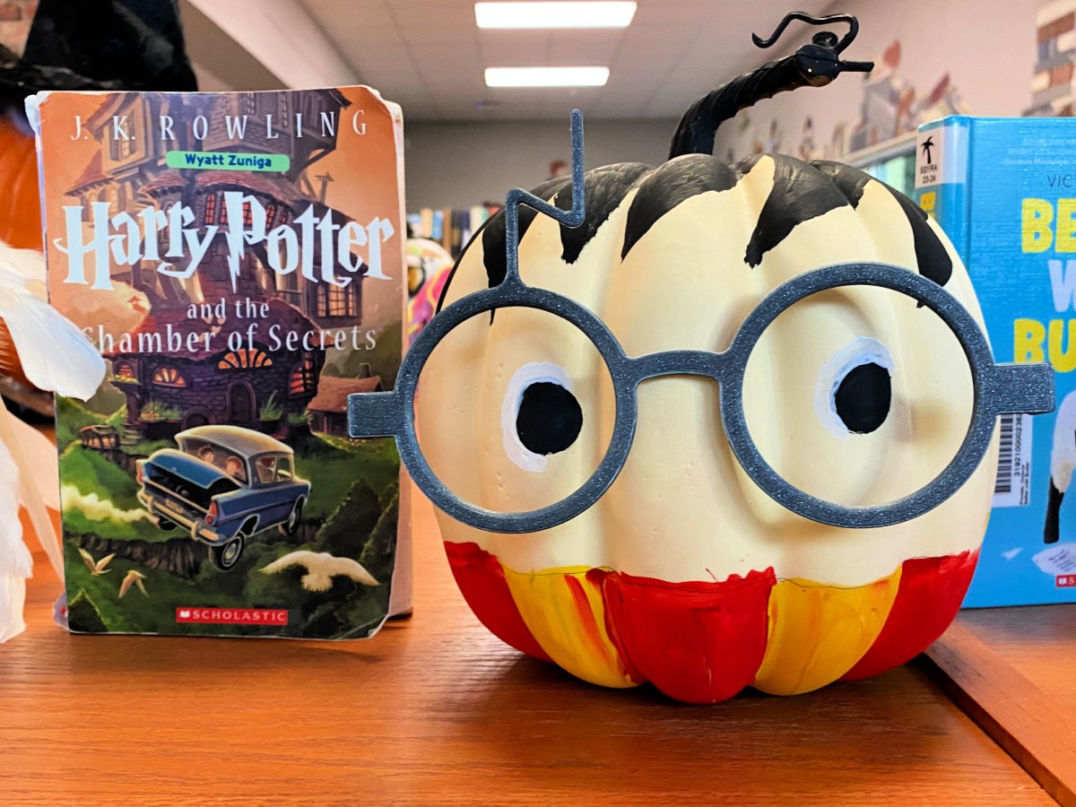 Harry Potter painted pumpkin next to a Harry Potter book.