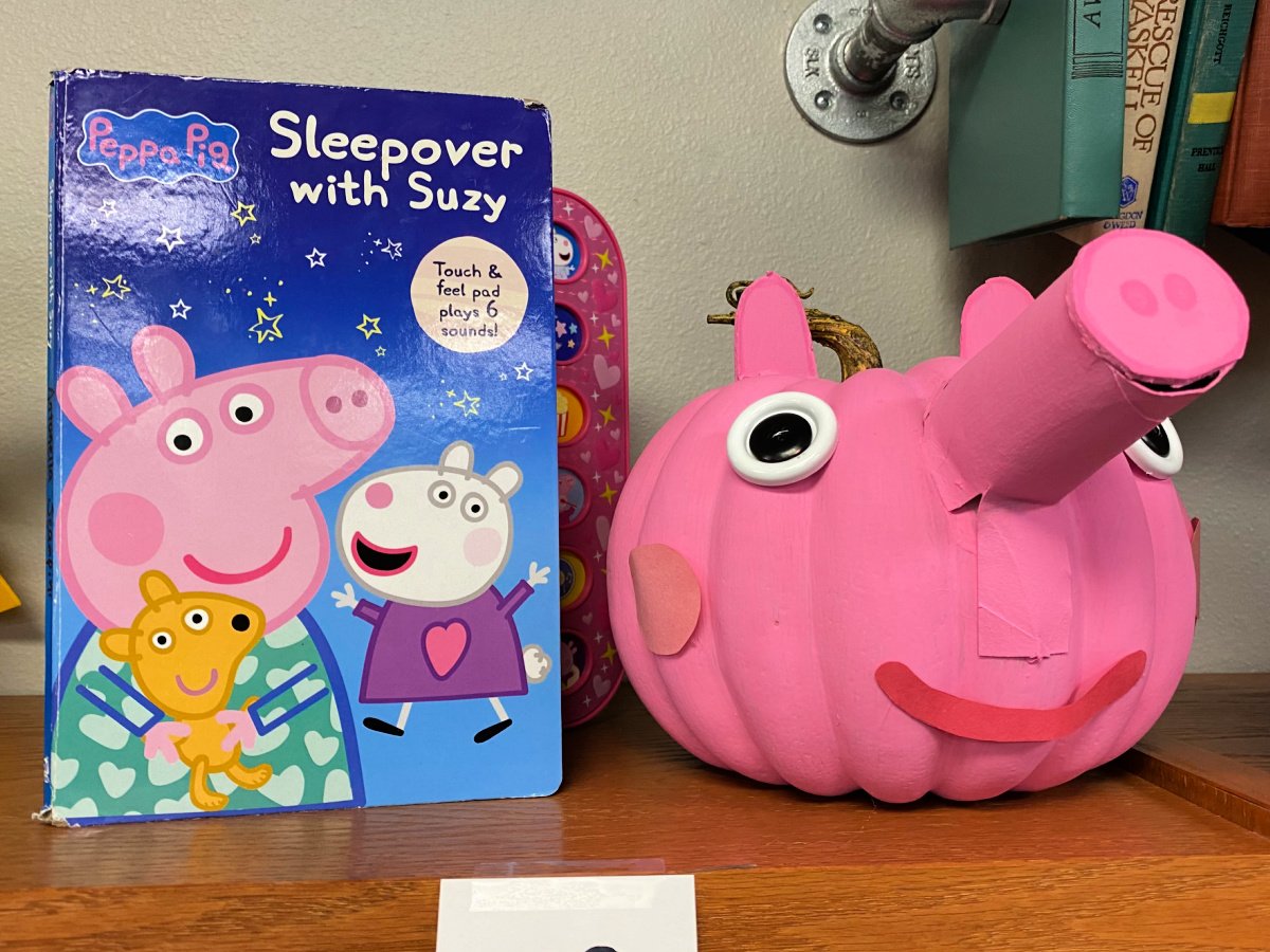 Pink Peppe Pig pumpkin next to a book.