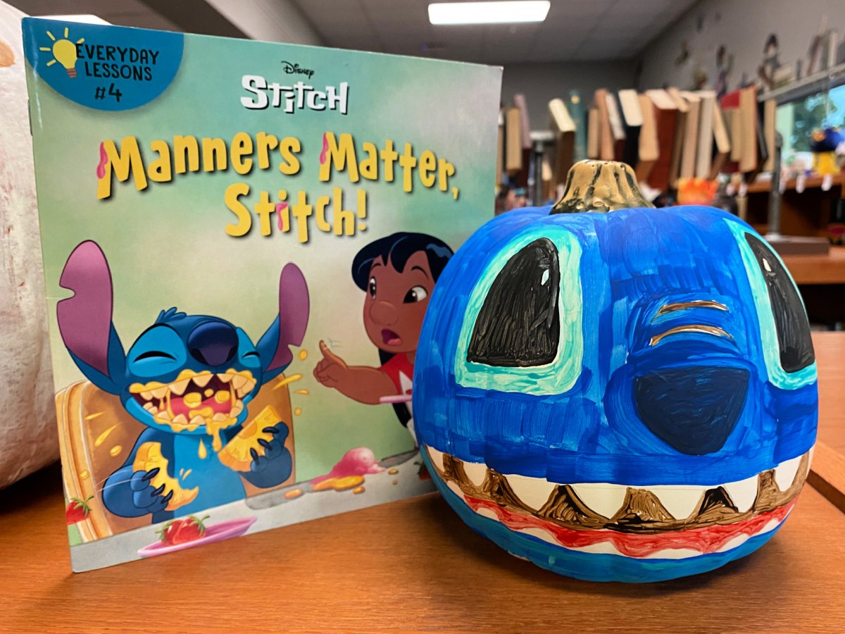 Blue Disney stitch pumpkin next to a Stitch book.