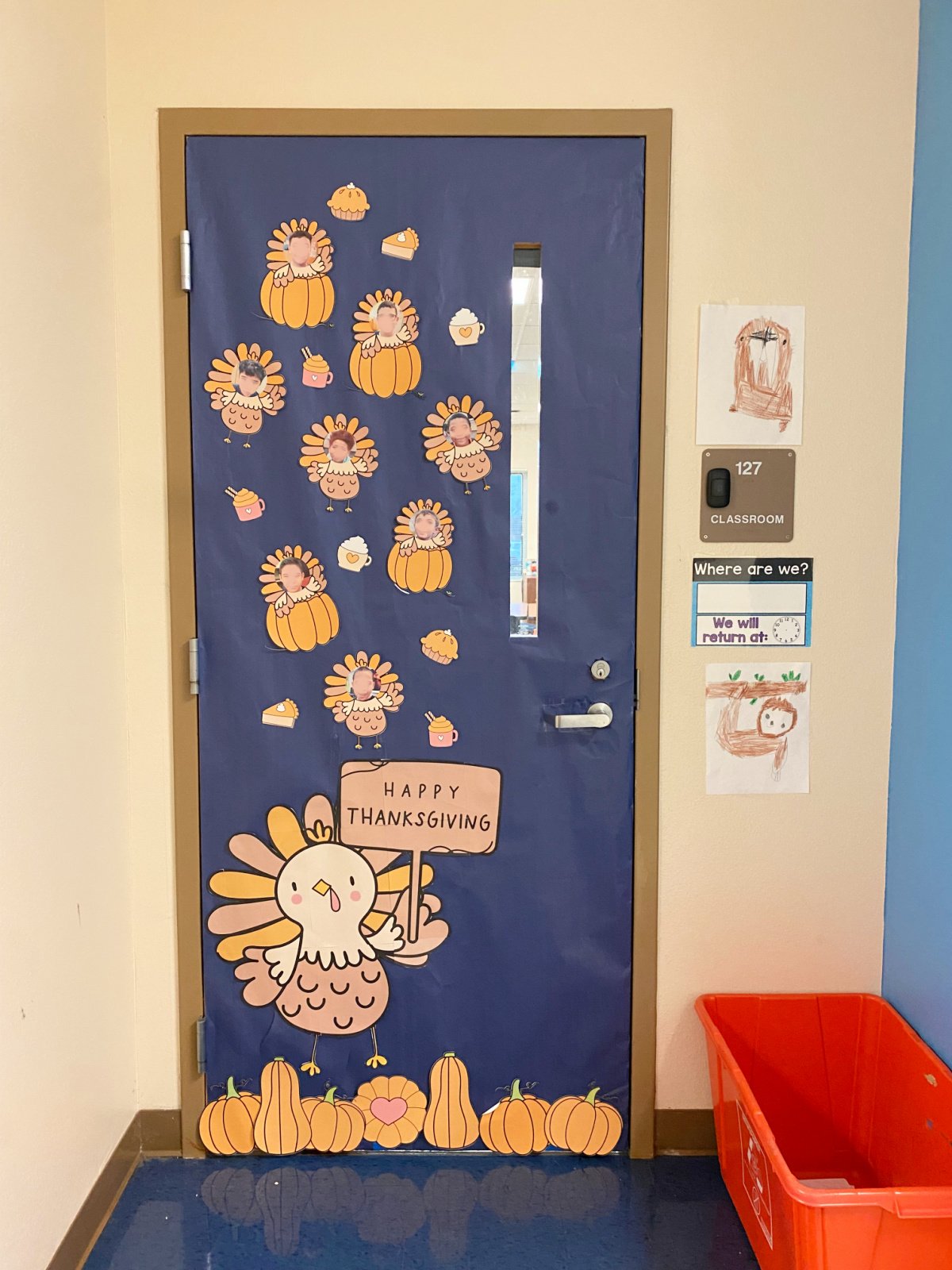 Blue classroom door decorated with a large turkey and small turkeys with kids faces on it.