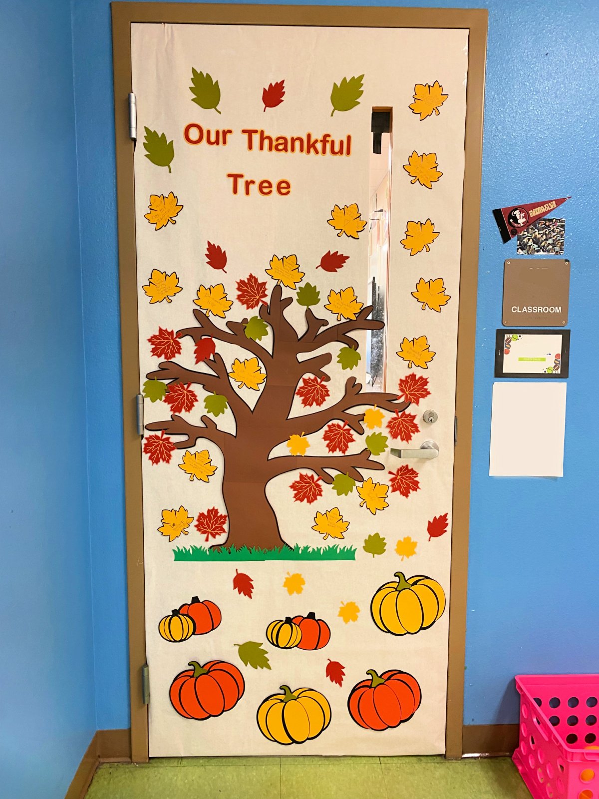 White classroom door with tree with fall leaves and pumpkins.