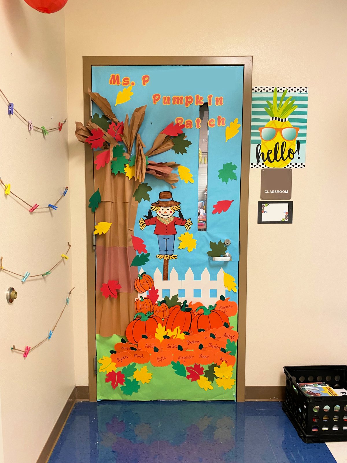 Tree with pumpkin patch, leaves, and a scarecrow decorated classroom door.