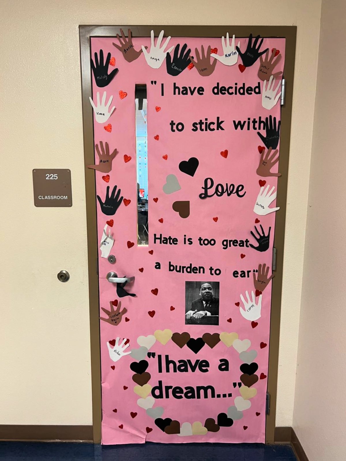 Pink door with hands cut out and names of kids on the door with a photo of MLK and "I have a dream" quote on door.